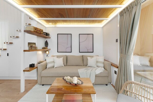A modern living room with a sofa, wooden coffee table, and decorative items on shelves.