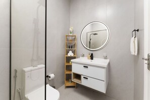 A modern bathroom with a toilet, sink, and shower. There is a wooden shelf with toiletries and a mirror above the sink.