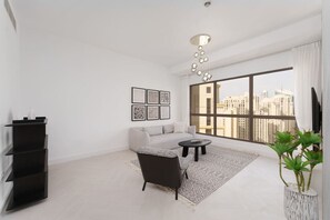 A modern living room with a sofa, a coffee table, a black bookshelf, and a large window with a city view.