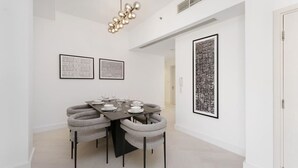 Ein Essbereich mit einem runden Tisch, grau gepolsterten Stühlen und gerahmten Kunstwerken an den Wänden.