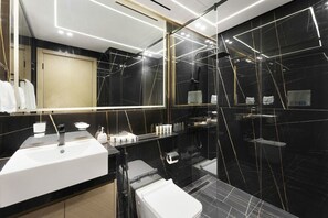 A modern bathroom with a large mirror, black marble walls, and a white sink.