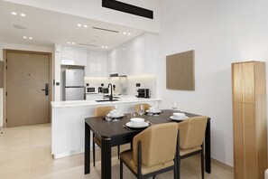 A modern kitchen with white cabinets, a black countertop, and a dining area with a table set for four.