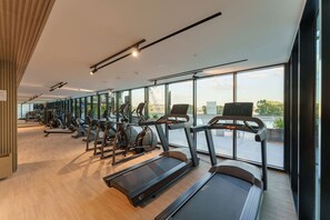 A modern gym with treadmills, elliptical machines, and free weights. - Premium Living Apartment in JVC by Suiteable (Dubai)