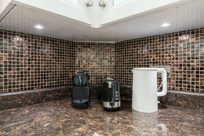 Eine Küche mit Kaffeemaschine, Wasserkocher und Tasse auf einer Granitarbeitsplatte.