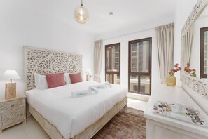 A hotel room with a large bed, a bedside table with a lamp, a window with curtains, and a view of the outside. - Green living chic 1 bedroom apartment (Dubai)