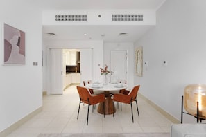 A modern dining area with a round table, orange chairs, and a decorative vase.