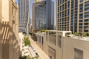 A modern high-rise building with a prominent "EDITION" sign, surrounded by other tall buildings and a street with parked cars.