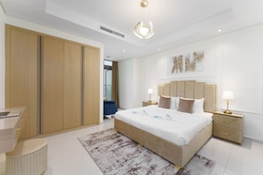 A modern hotel room with a large bed, bedside tables, a desk, and a wardrobe.