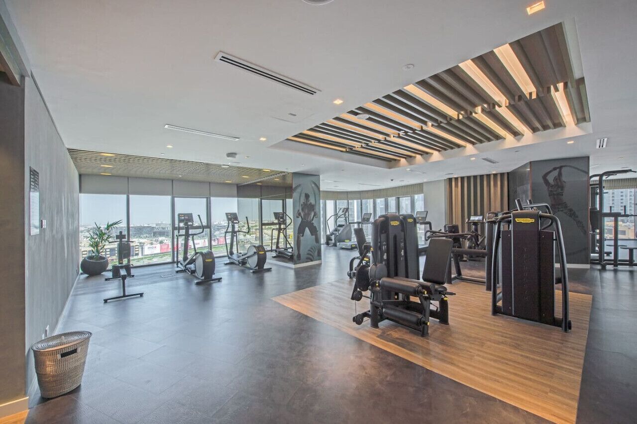 Ein modernes Fitnessstudio mit unterschiedlichen Trainingsgeräten, großen Fenstern und Blick auf die Stadt.