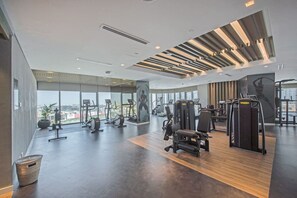 Ein modernes Fitnessstudio mit unterschiedlichen Trainingsgeräten, großen Fenstern und Blick auf die Stadt.