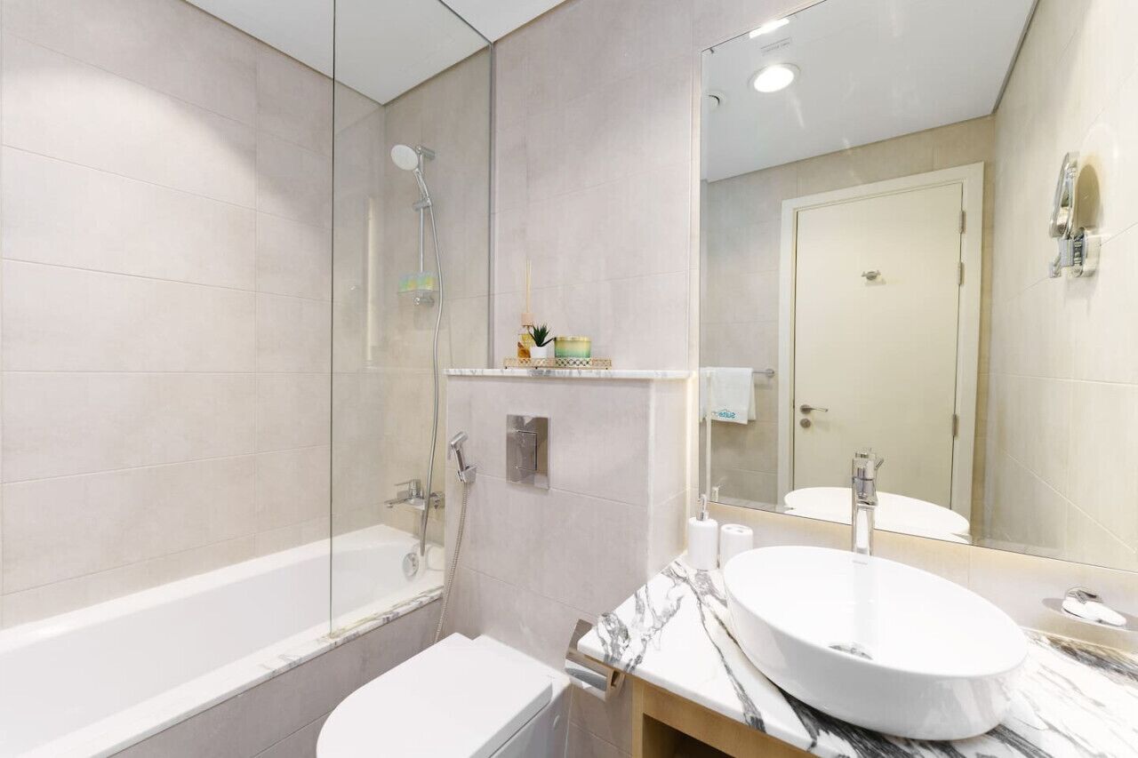 A modern bathroom with a bathtub, a sink, and a large mirror.