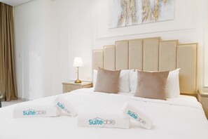 Ein Hotelzimmer mit einem großen Bett, einem mehrteiligen Kopfteil, einem Nachttisch mit Lampe und einem Gemälde an der Wand.