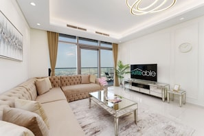 A modern living room with a large sofa, a glass coffee table, and a flat-screen TV.