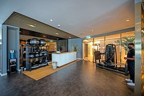 A modern gym with exercise equipment, a reception desk, and a water dispenser.
