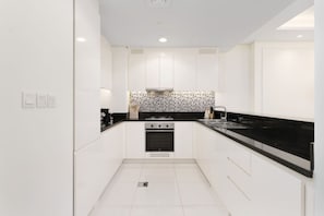 A modern kitchen with white cabinets, a black countertop, and a patterned backsplash.