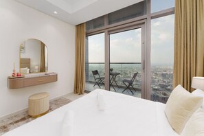 Ein Hotelzimmer mit einem großen Bett, einem Frisiertisch mit Spiegel, einem kleinen Hocker und einem Balkon mit Stühlen.