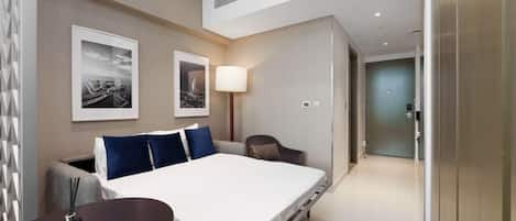 Une chambre d’hôtel moderne, équipée d’un lit, d’un bureau, d’une chaise et de deux tableaux encadrés accrochés au mur.