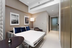 Habitación de hotel moderna con cama, escritorio, silla y dos cuadros en la pared.