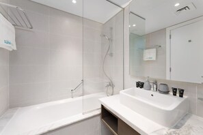 A modern bathroom with a glass-enclosed shower, a white sink with toiletries, and a large mirror. - Your Dream Home in Damac Maison Prive by Suiteable (Dubai)