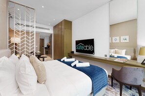 A hotel room with a bed, a desk, a chair, a TV, and a wall-mounted artwork. - Your Dream Home in Damac Maison Prive by Suiteable (Dubai)