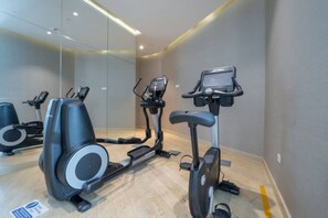 A gym with stationary bikes and a treadmill, mirrored walls, and a clean, modern design.