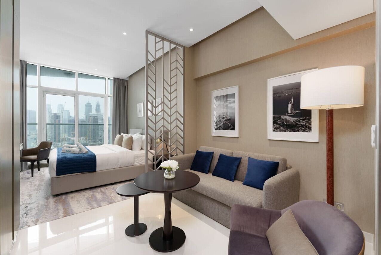 Une chambre d’hôtel moderne avec un grand lit, un canapé, une table basse et une vue sur la ville.