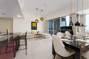 A modern living room with a dining area, a kitchen, and a large window with curtains.