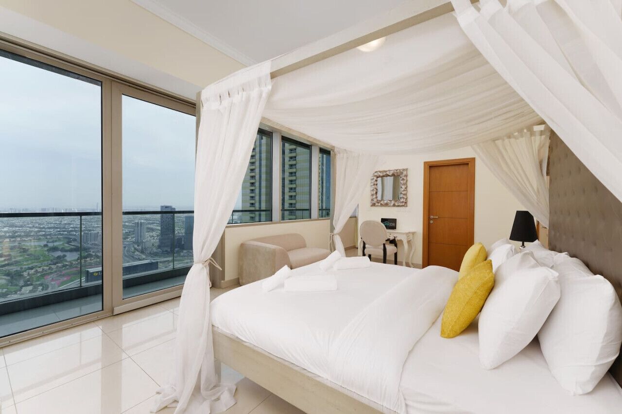 Une chambre avec un grand lit, une vue sur la ville et un balcon.