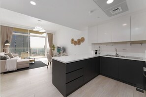 A modern kitchen with a central island, white cabinetry, and a large window offering a city view.