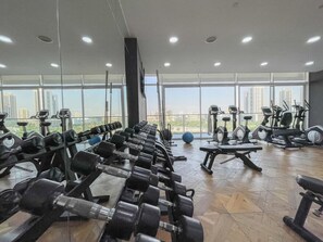 Un gimnasio con filas de mancuernas, cintas de correr y pelotas de ejercicio.