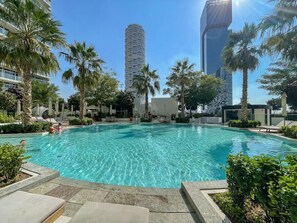 A swimming pool surrounded by palm trees and modern buildings.