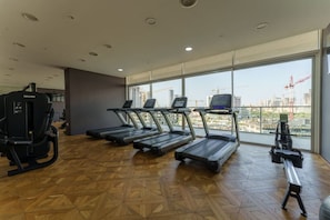 Une salle de sport équipée de tapis de course, d’un rameur et d’autres appareils d’exercice.