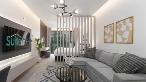 A modern living room with a grey sofa, a glass coffee table, and a flat-screen TV mounted on the wall. - Luxury Redefined Studio in AHAD Residence (Business Bay)