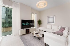 A modern living room with a flat-screen TV, white sofa, and a coffee table.