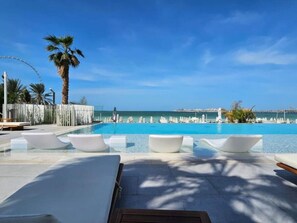 A poolside area with lounge chairs and a view of the sea.