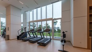 A gym with treadmills, a stationary bike, and a rowing machine. - Beachfront Luxury Living at La Vie Residence JBR (Dubai)