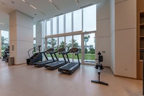 Une salle de sport équipée de tapis de course, d’un vélo d’appartement et d’un appareil d’aviron.