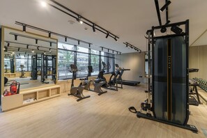 Uma academia com equipamentos de ginástica, espelhos e uma grande janela.