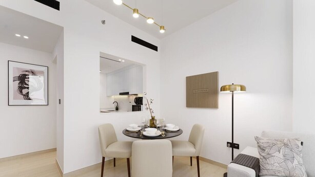 A modern dining area with a round table set for four, a sofa, a floor lamp, and a wall-mounted artwork.