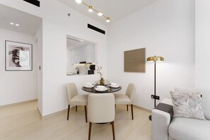 Un comedor moderno con una mesa redonda preparada para cuatro personas, un sofá, una lámpara de pie y una obra de arte colgada en la pared.