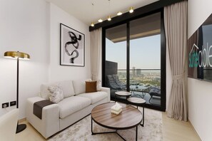 A modern living room with a sofa, coffee table, and large windows offering a city view. - Experience Serenity at Binghatti Crest in JVC (Dubai)