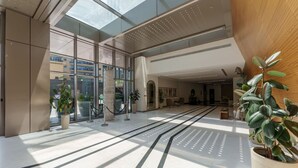 Eine großzügige Lobby mit hoher Decke, großen Fenstern und einer zentralen Säule.