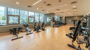 Ein Fitnessstudio mit Trainingsgeräten, großen Fenstern und Blick auf Gebäude.