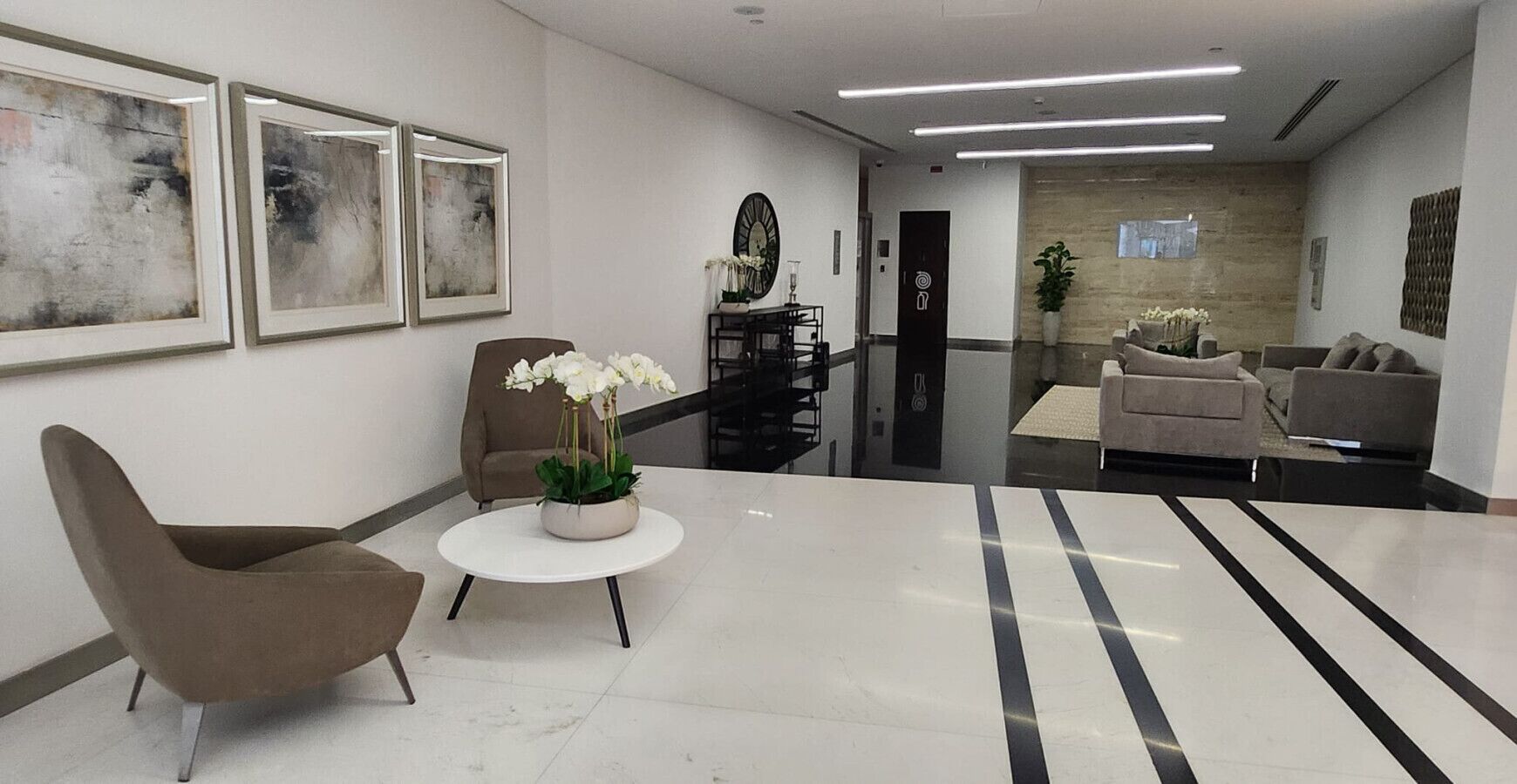 A modern lobby with a reception desk, seating area, and artwork on the walls.