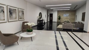 Un vestíbulo moderno con mostrador de recepción, zona de estar y obras de arte en las paredes.