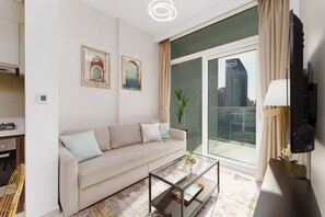 A modern living room with a sofa, a glass coffee table, and a large window with a city view.