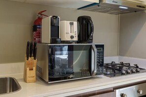 A kitchen with a microwave, a coffee maker, a gas stove, and a fire extinguisher. - Contemporary Apartment with Burj Khalifa View (Dubai)