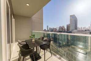A balcony with a city view, a table, and chairs.