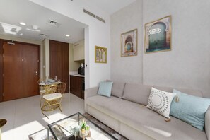 A living room with a sofa, a dining table with chairs, and a kitchen area in the background. - Contemporary Apartment with Burj Khalifa View (Dubai)