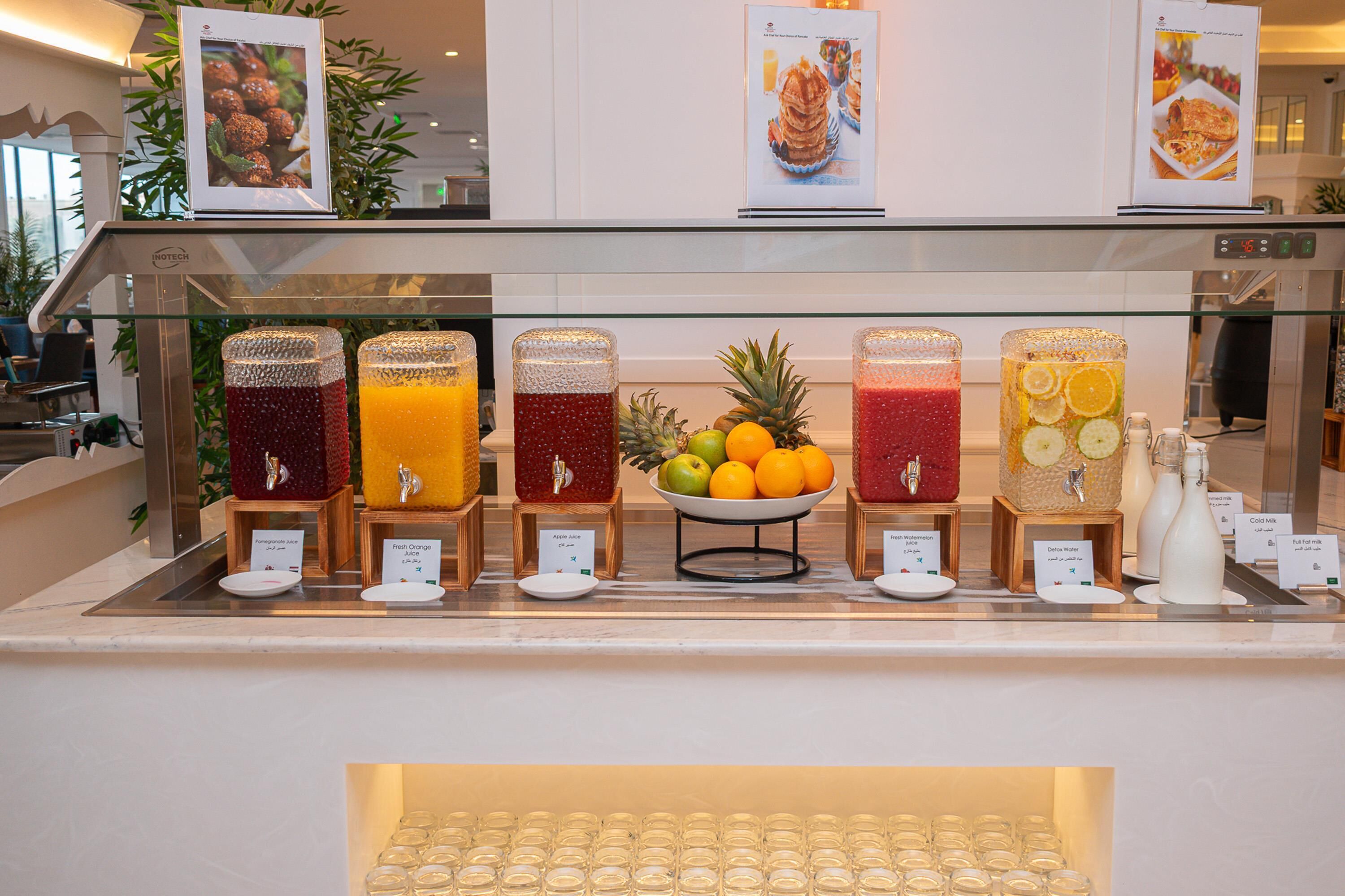 A juice bar with various fruit juices and a bowl of fruits.